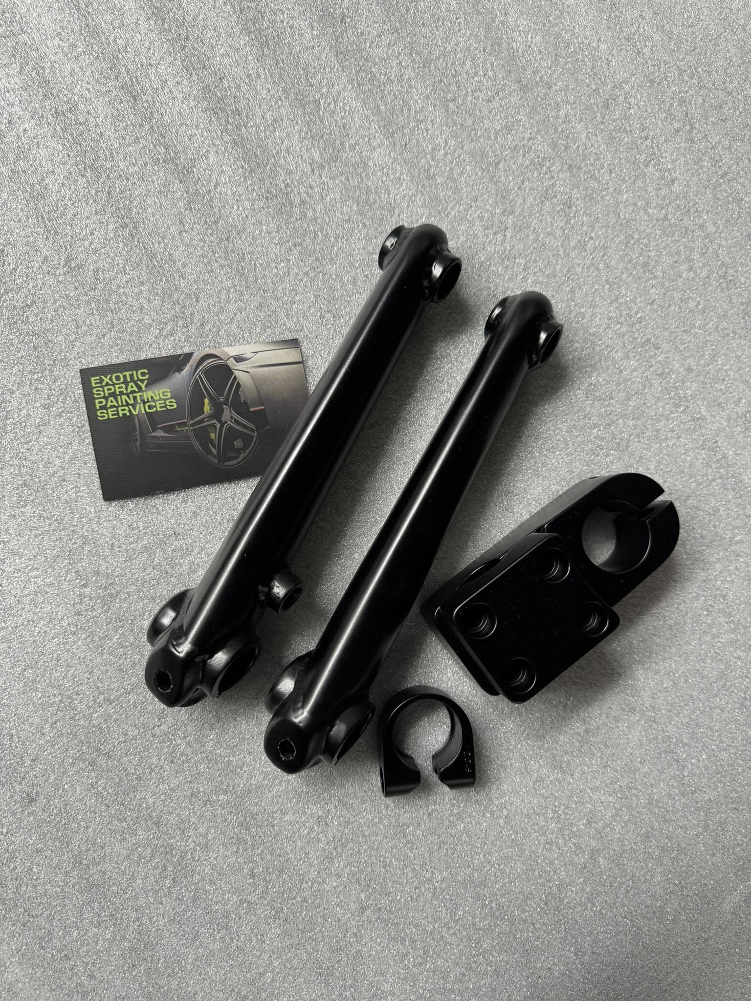 Satin black refinished small parts laid out on a grey surface