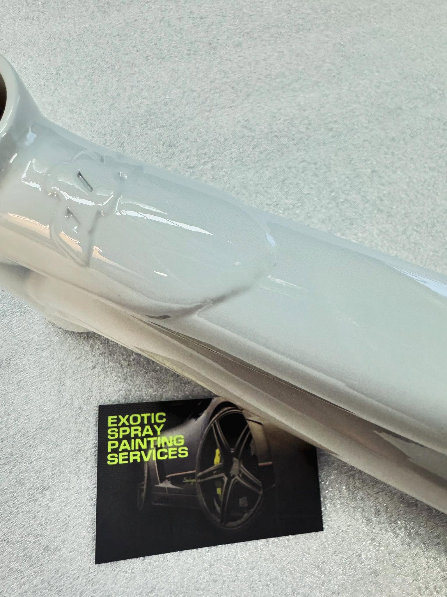 Gloss white painted metal part resting on a grey surface